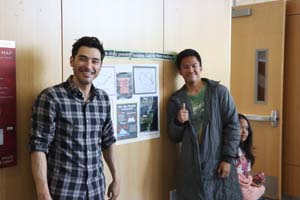 two male individuals standing in front of poster