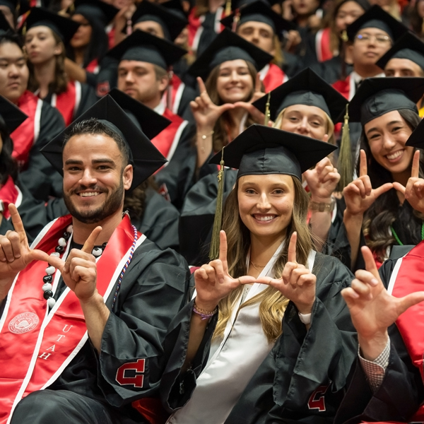 view of graduates sitting at the ceremony making the U with their fingers